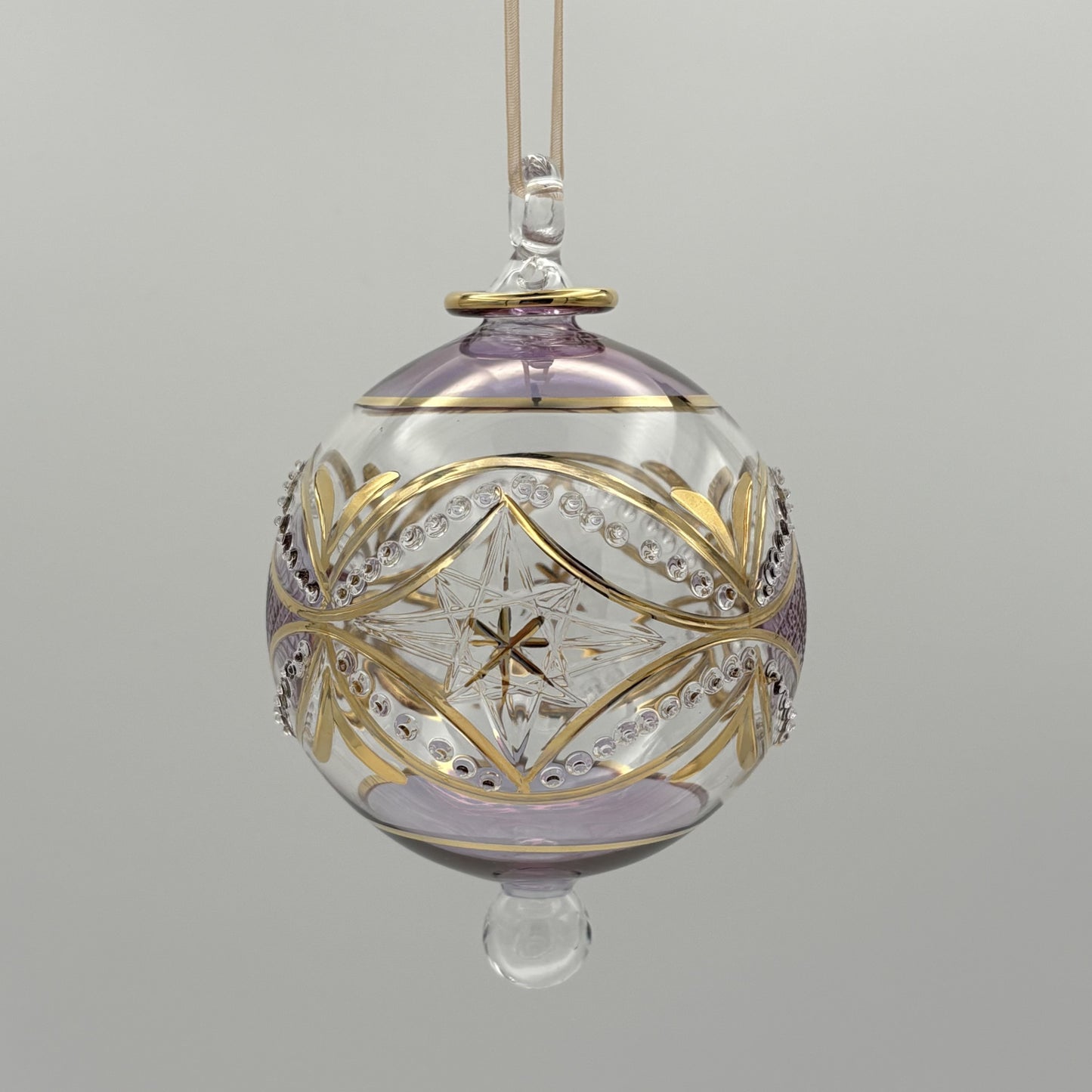 Handblown glass ornament with carousel and stars design with tops hand painted in lavender and with gold highlights