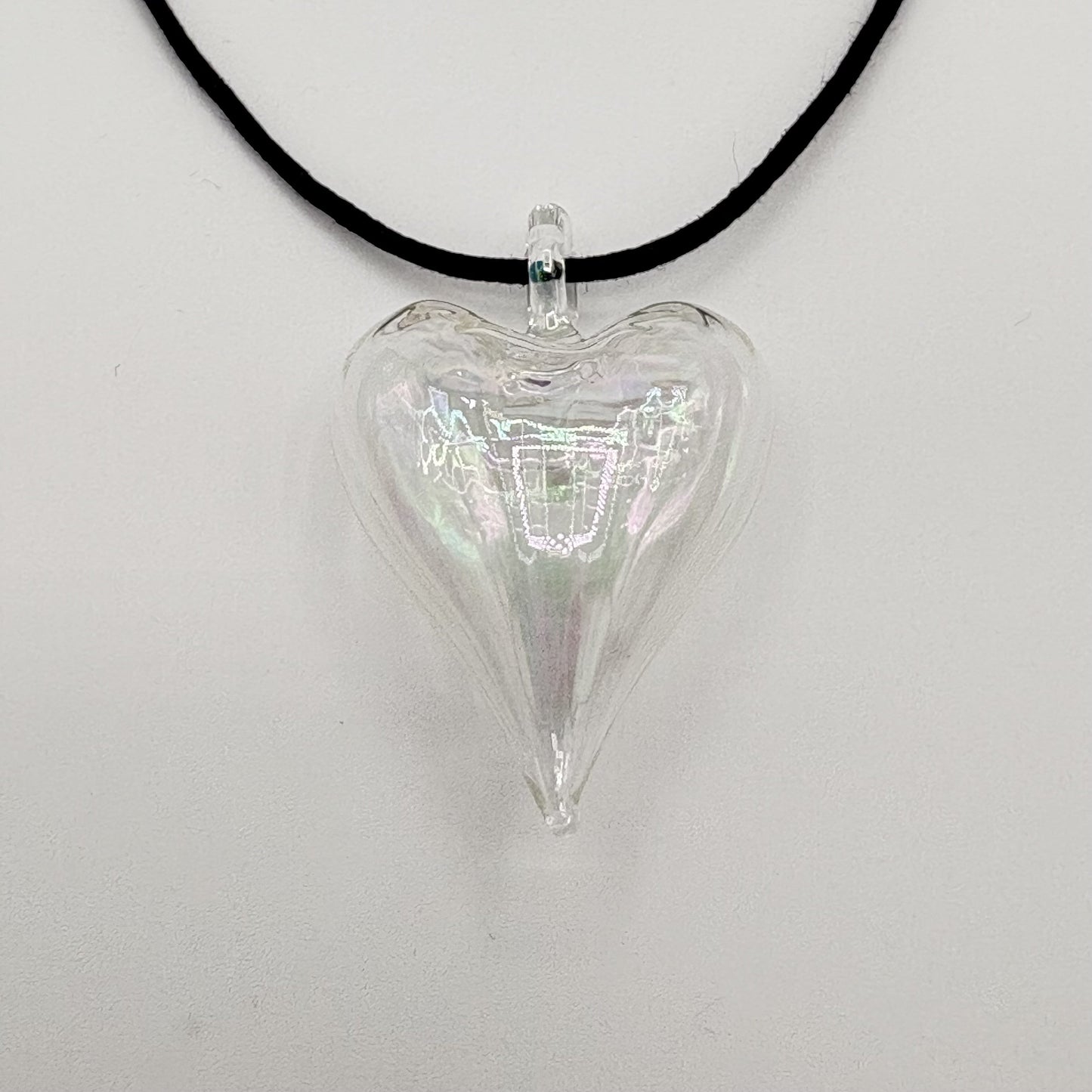 Heart-shaped iridescent clear hand-blown glass pendant on a black cord