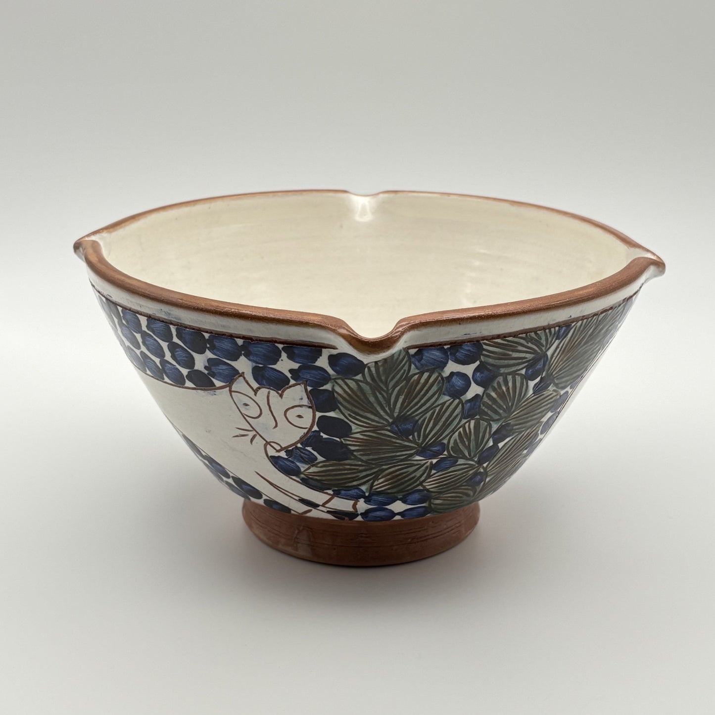 Handmade fair trade ceramic bowl with bouncing cat on a blue and white floral design