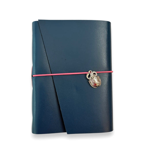 Handbound dark blue leather journal with a diagonal fold closure, secured by an elastic band featuring a silver scarab charm