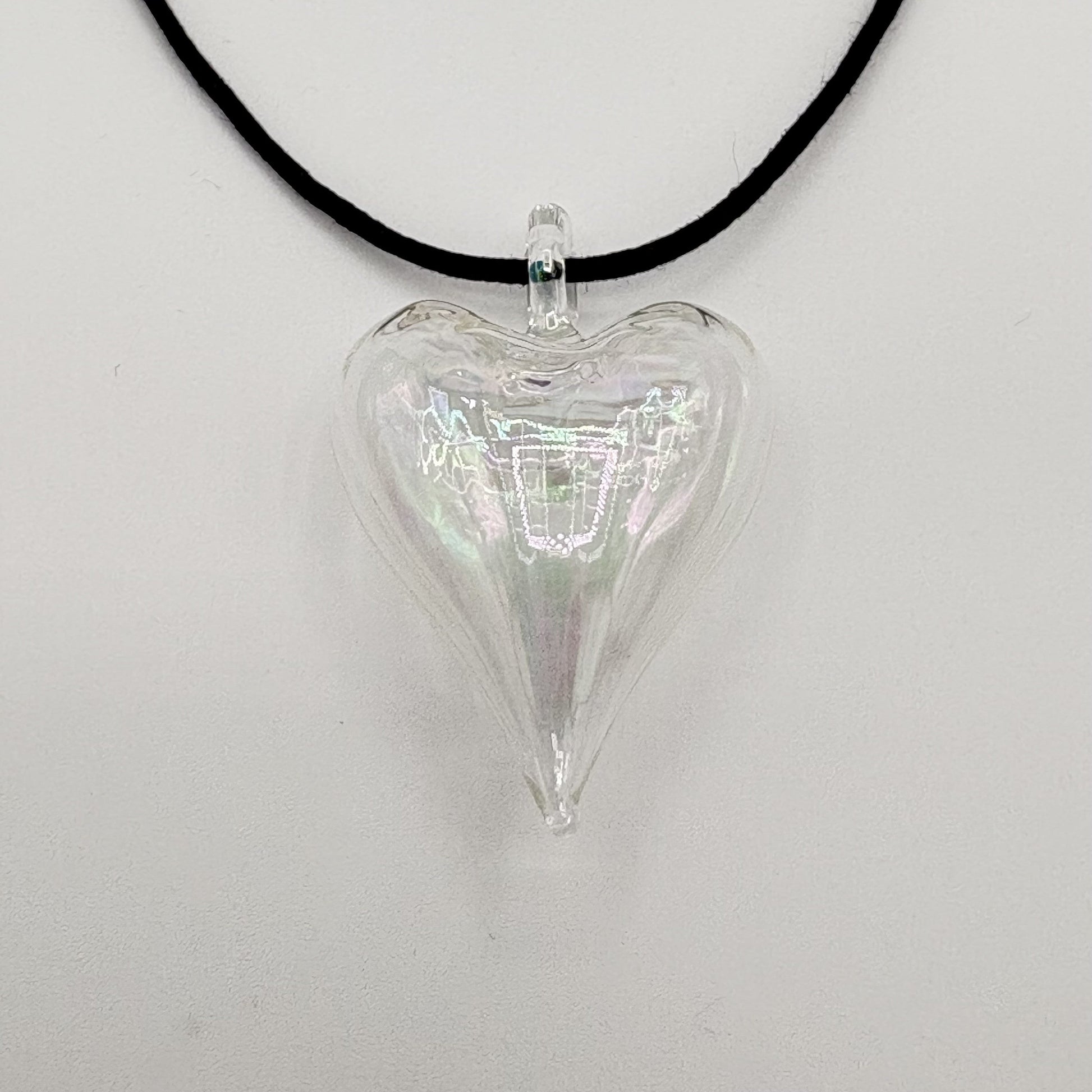 Heart-shaped iridescent clear hand-blown glass pendant on a black cord