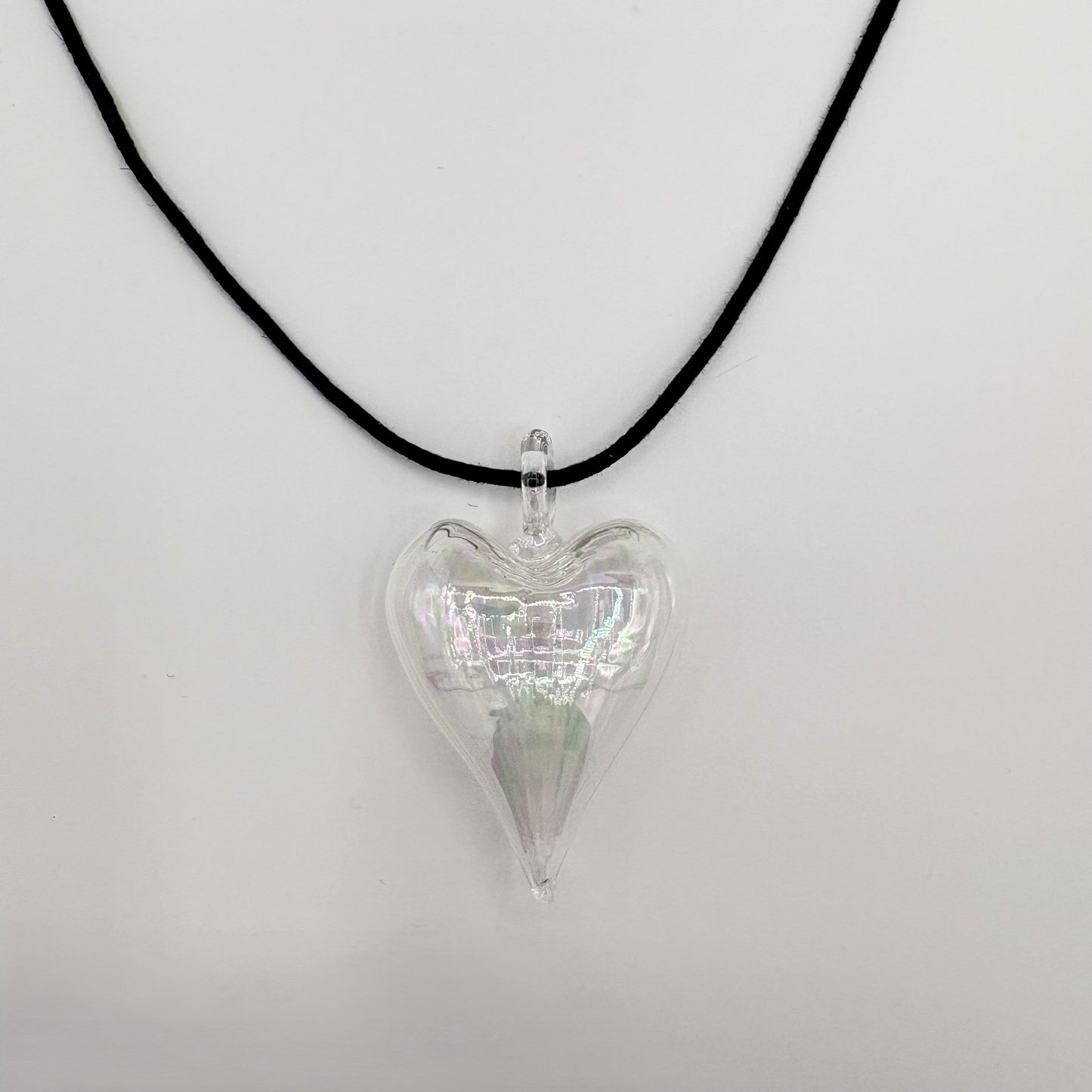 Heart-shaped iridescent clear hand-blown glass pendant on a black cord