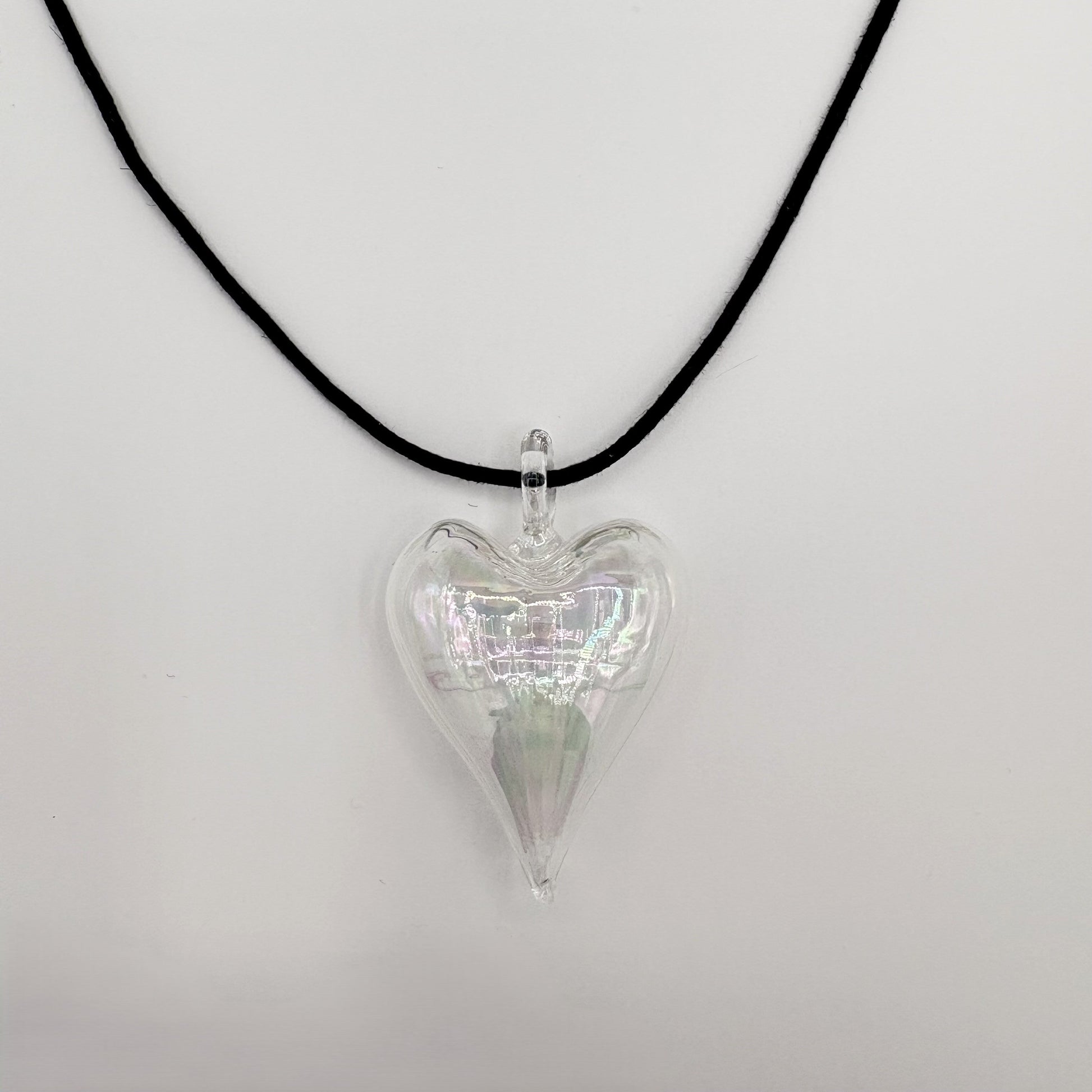 Heart-shaped iridescent clear hand-blown glass pendant on a black cord