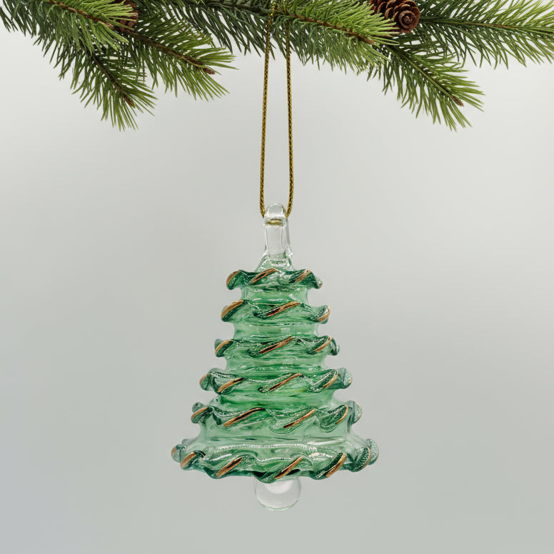 Green blown glass Christmas tree ornament hanging from a branch with pine cones.