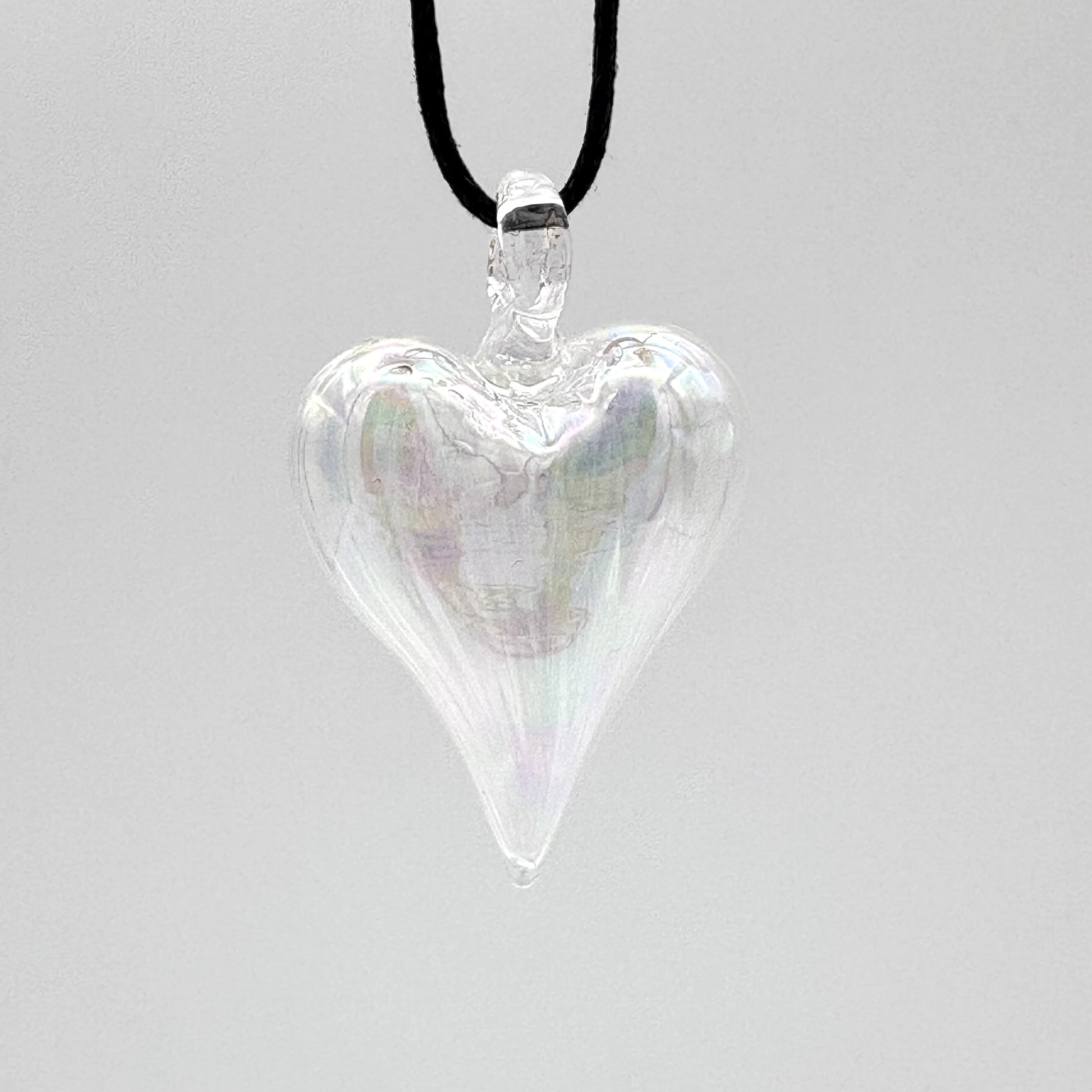 Heart-shaped iridescent clear hand-blown glass pendant on a black cord