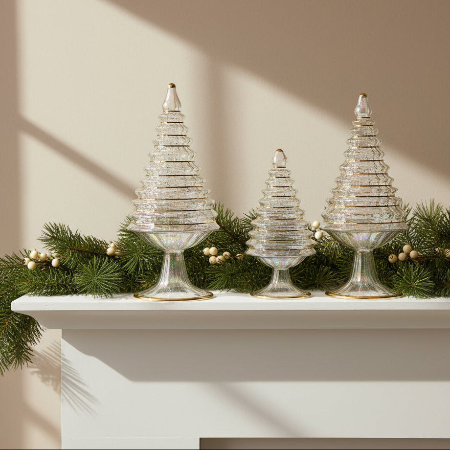 Decorative mouth-blown glass Christmas trees on a mantelpiece with greenery and berries. Fair trade, ethically handcrafted