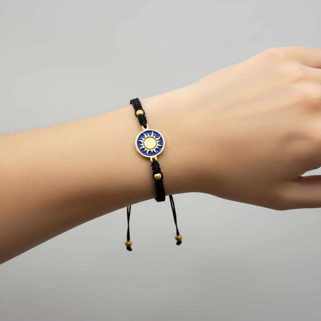 Black macrame bracelet with a brass medallion featuring a gold sun emblem on blue enamel
