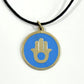 Handmade brass pendant with gold Hamsa hand on turquoise enamel on a black cord, fair trade, ethically handmade
