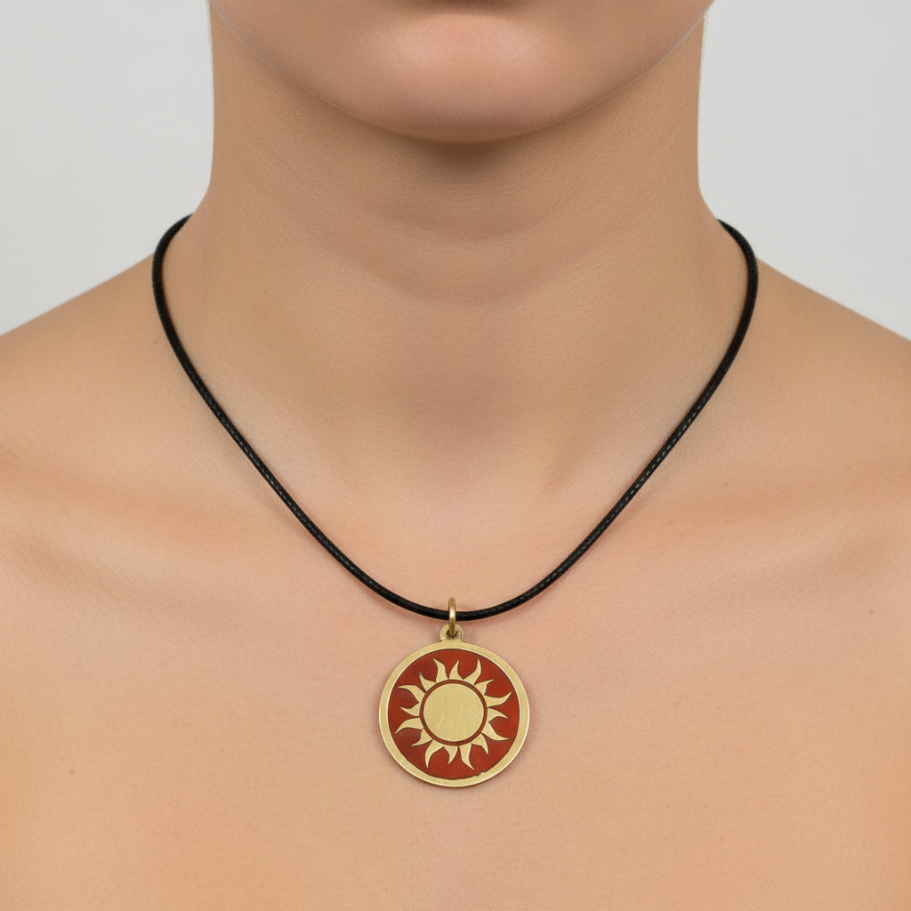 Necklace with a handmade brass pendant featuring gold sun against maroon enamel, fair trade