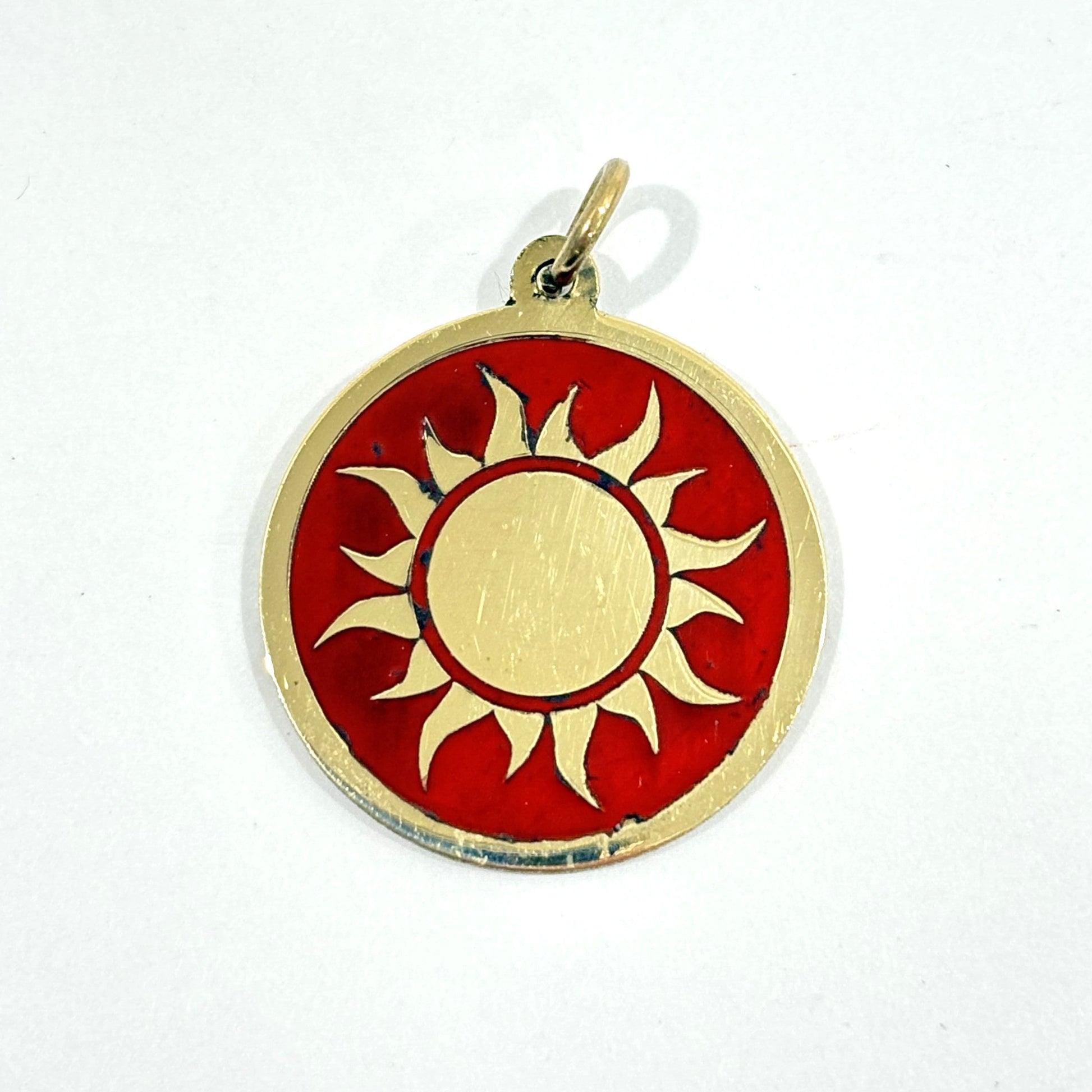 Fair trade handmade brass pendant featuring gold sun against maroon enamel