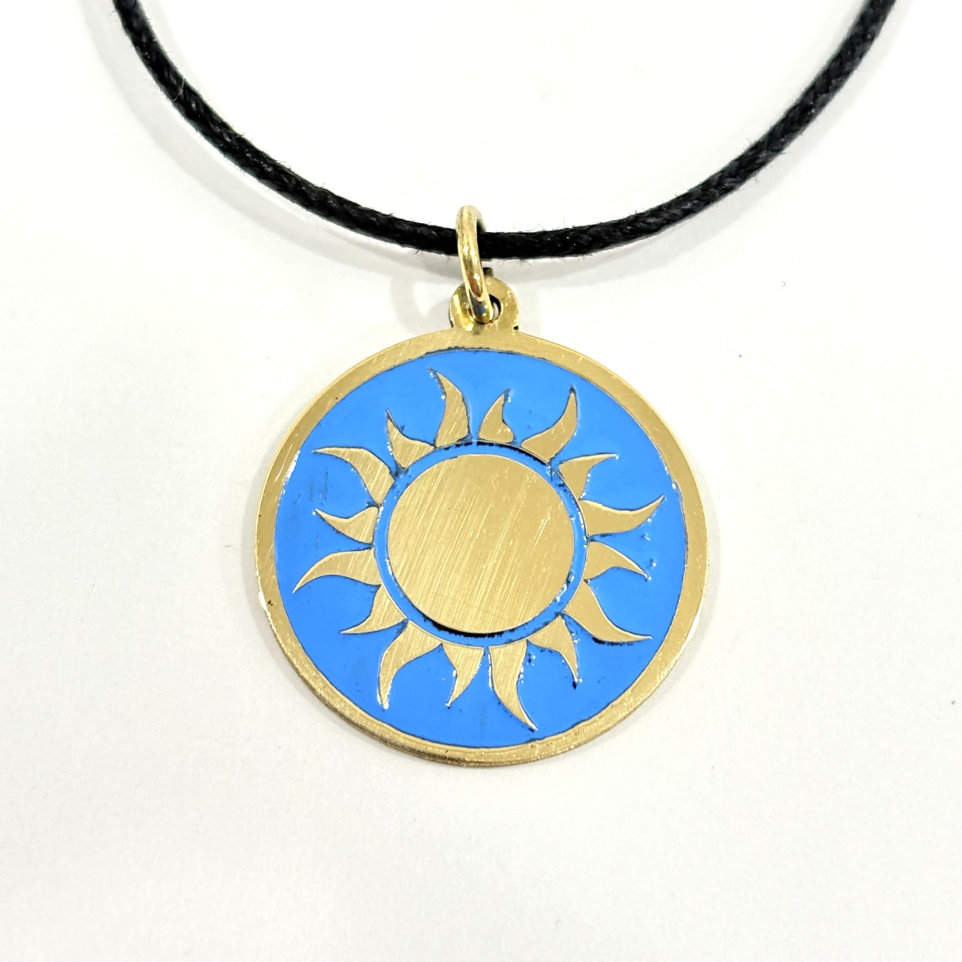 Handmade brass gold sun pendant on a turquoise blue enamel background with a black cord