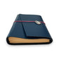 Handbound dark blue leather journal with a diagonal fold closure, secured by an elastic band featuring a silver scarab charm