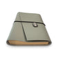 Gray handbound leather notebook with a diagonal fold design, wrapped with a pink elastic cord and featuring a silver-toned scarab charm