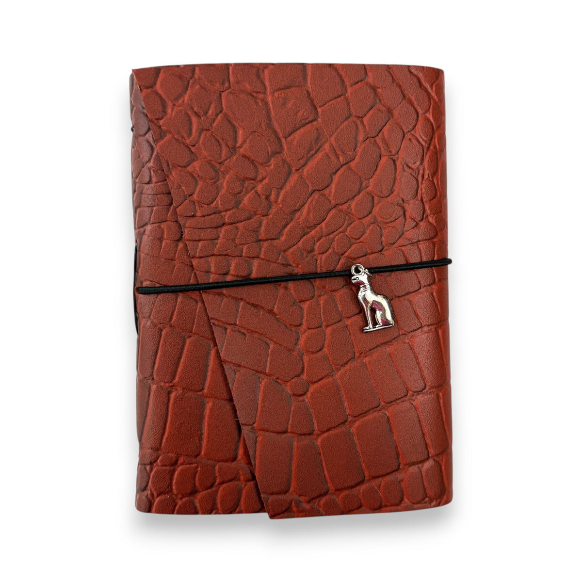 Rust red handbound leather journal with a wrap-around elastic strap and a silver metal cat goddess Bastet Charm