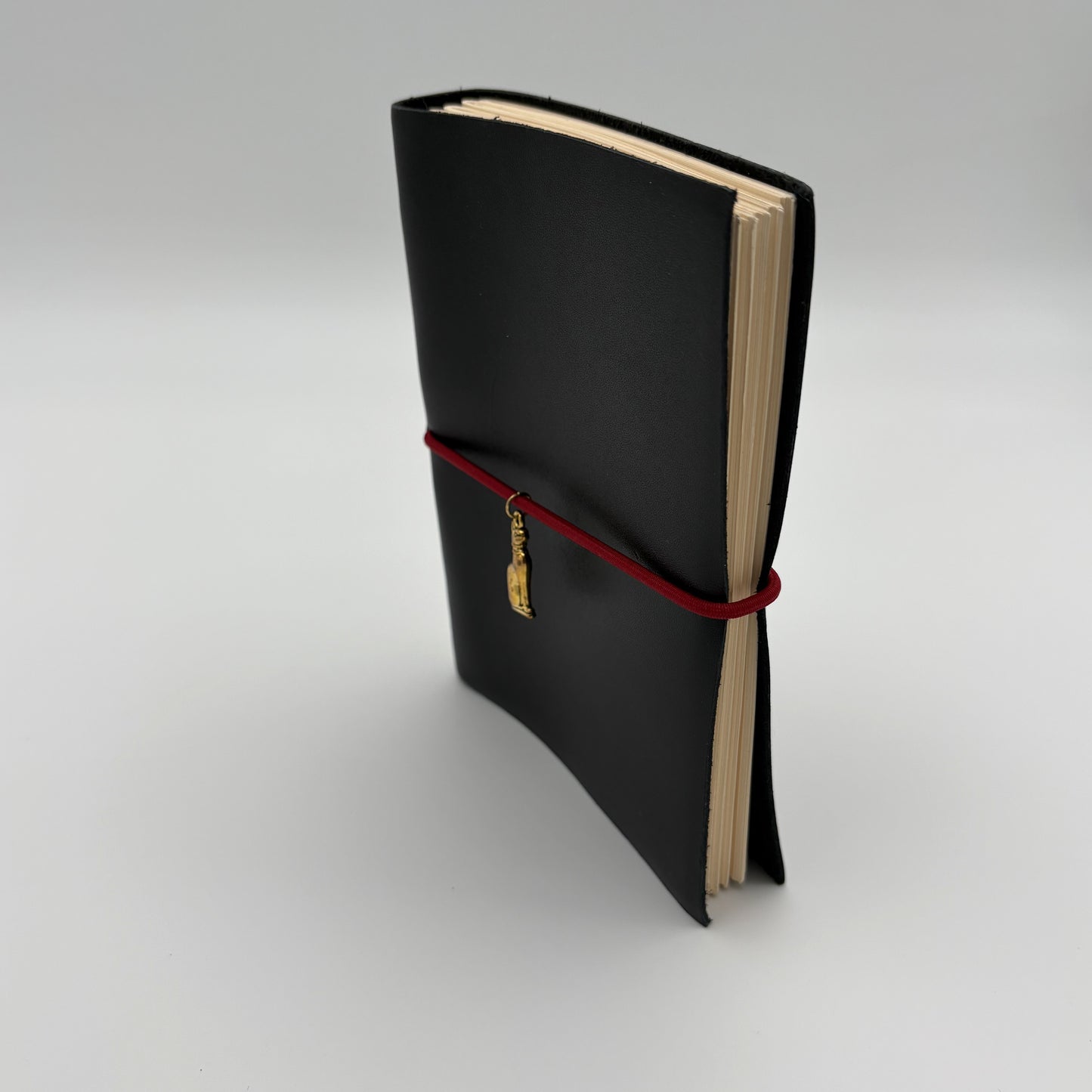 Handcrafted black leather journal with red string and gold Bastet cat charm, cruelty-free, fair trade, ethically handmade