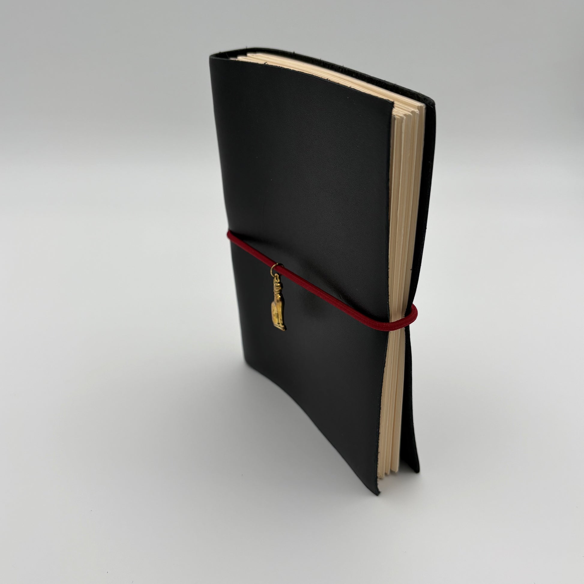 Handcrafted black leather journal with red string and gold Bastet cat charm, cruelty-free, fair trade, ethically handmade