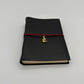Handcrafted black leather journal with red string and gold Bastet cat charm, cruelty-free, fair trade, ethically handmade