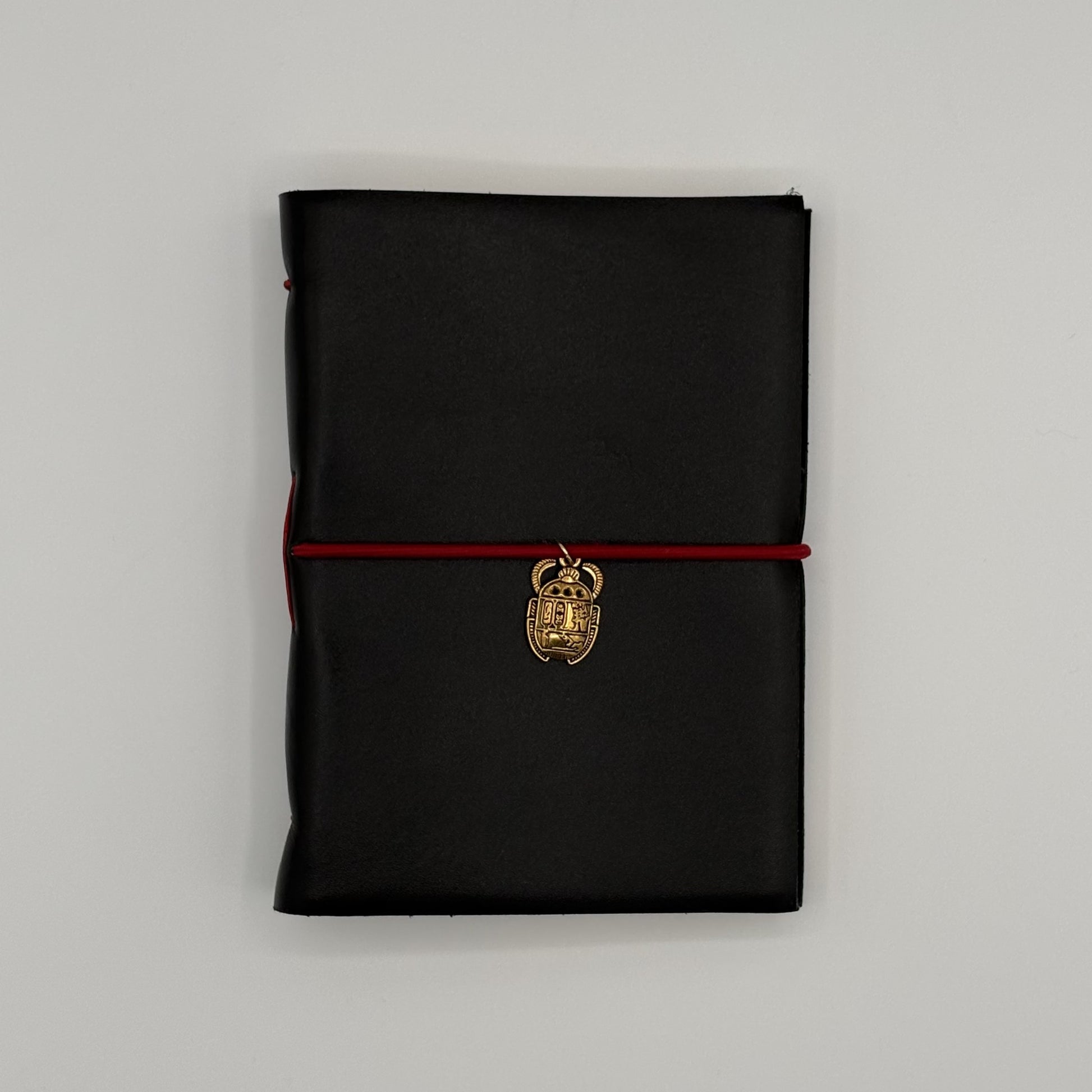 Handcrafted black leather journal with red string and gold Scarab charm, cruelty-free, fair trade, ethically handmade