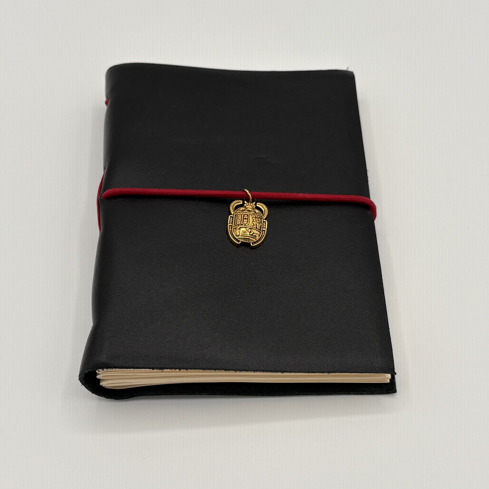 Handcrafted black leather journal with red string and gold Scarab charm, cruelty-free, fair trade, ethically handmade