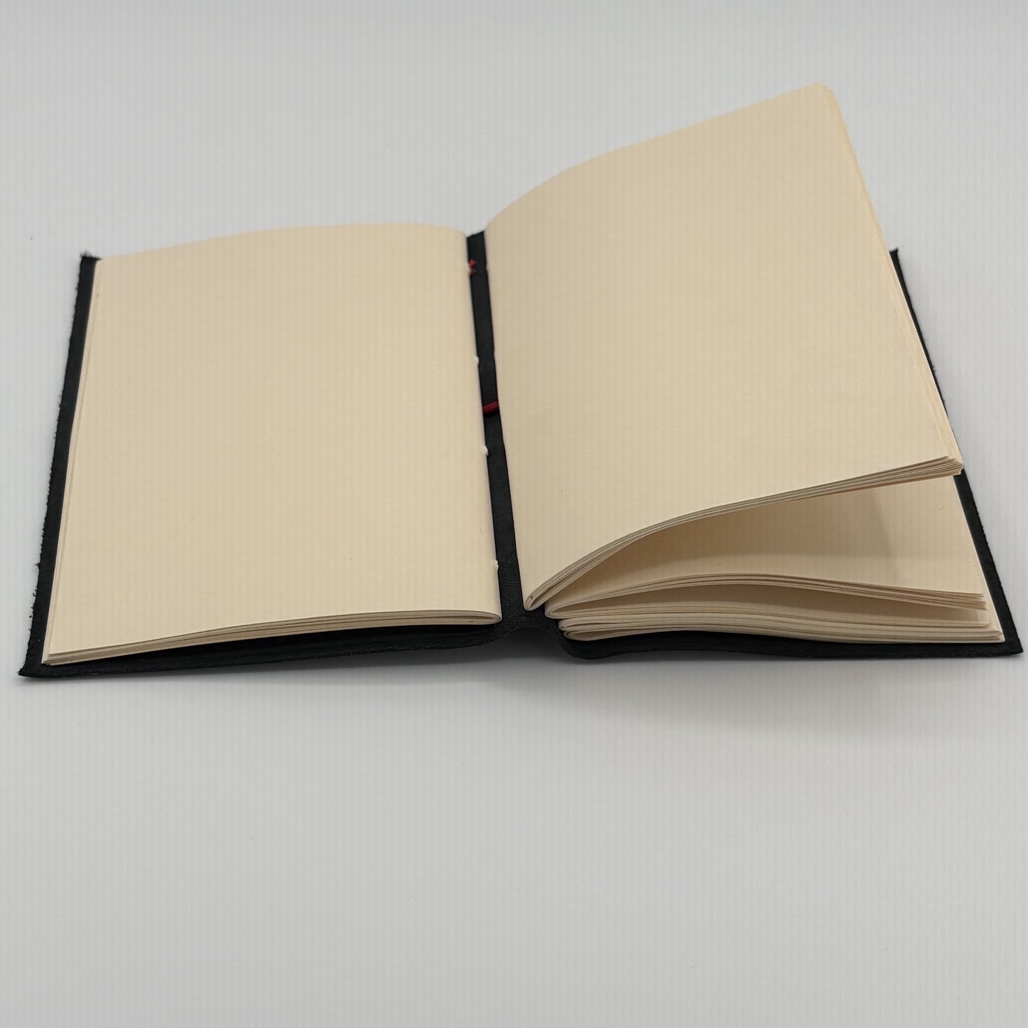 Handcrafted black leather journal with red string Coptic stitching, cruelty-free, fair trade, ethically handmade