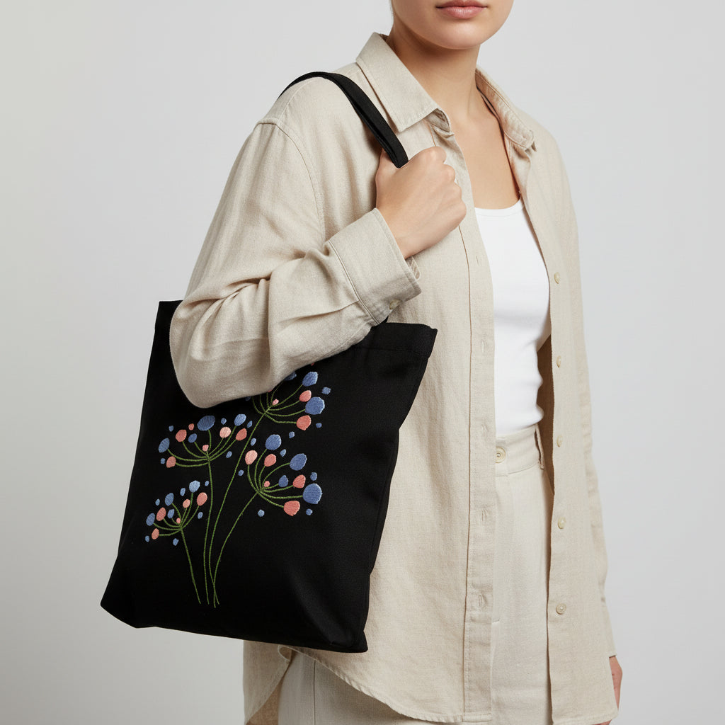 Handmade black tote bag with hand-embroidered light blue and pink hydrangea, fair trade