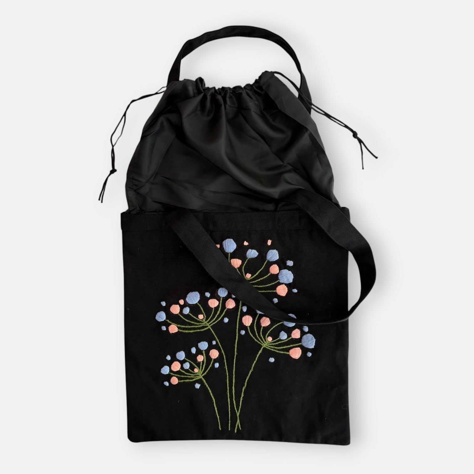 Handmade black tote bag with hand-embroidered light blue and pink hydrangea, fair trade