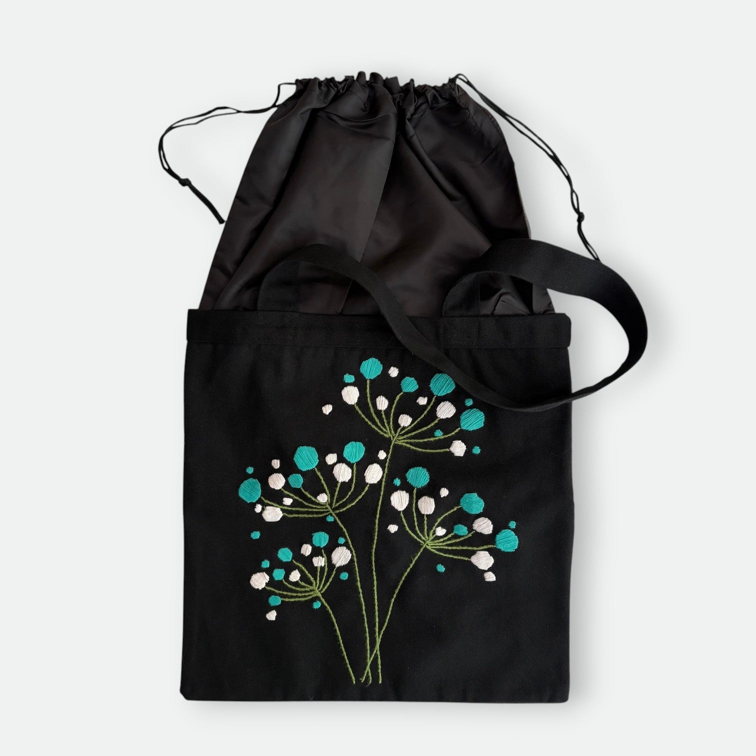 Handmade black tote bag with hand-embroidered white and turquoise hydrangea, fair trade