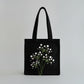 Handmade black tote bag with hand-embroidered white hydrangea, fair trade