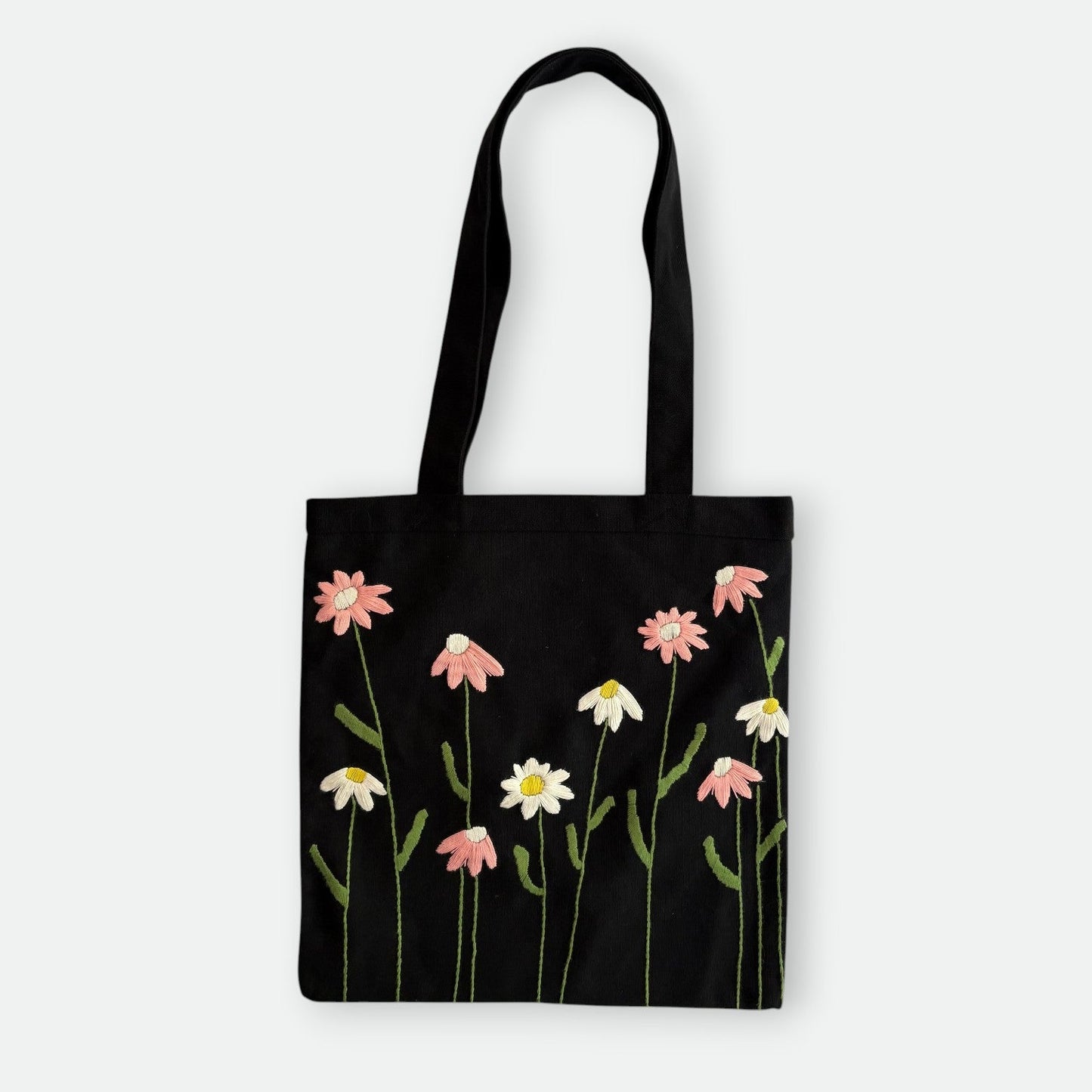 Handmade black tote bag with hand-embroidered pink and white marguerite, fair trade