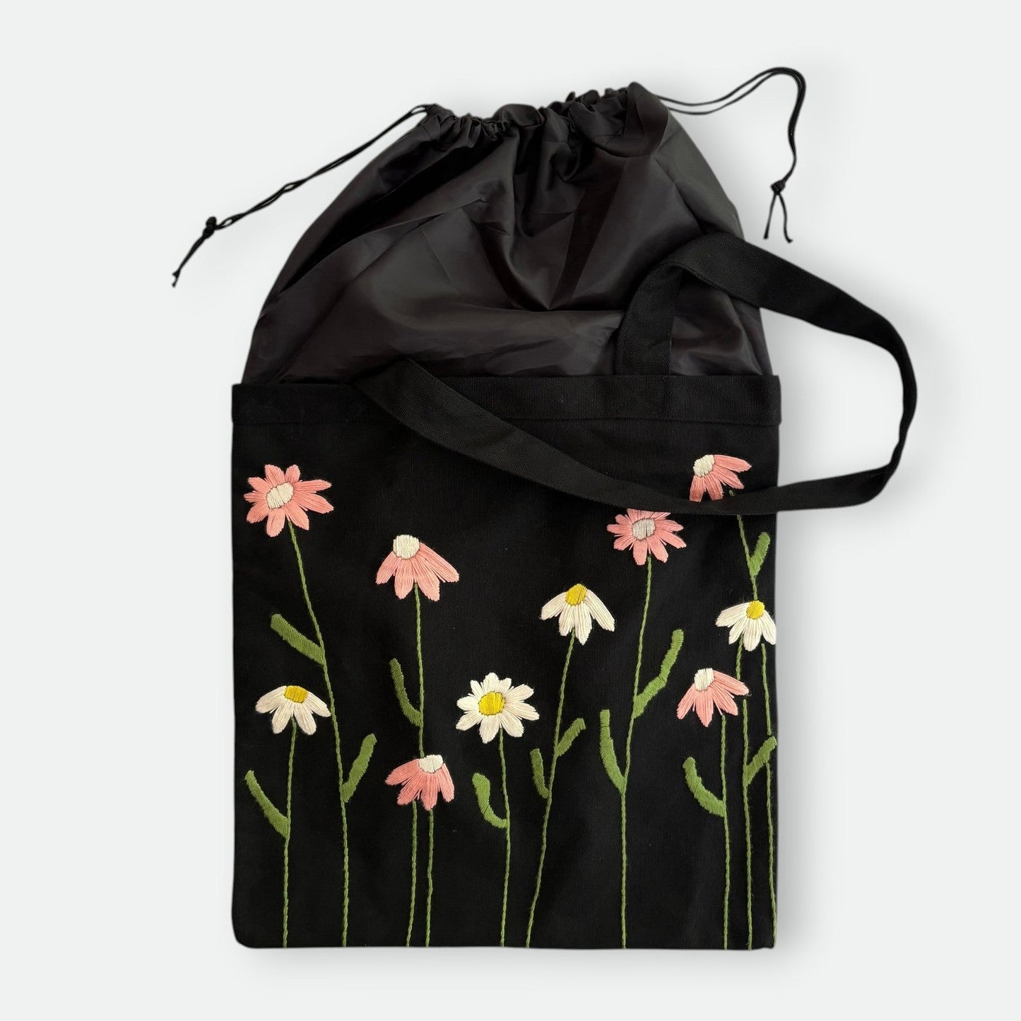 Handmade black tote bag with hand-embroidered pink and white marguerite, fair trade