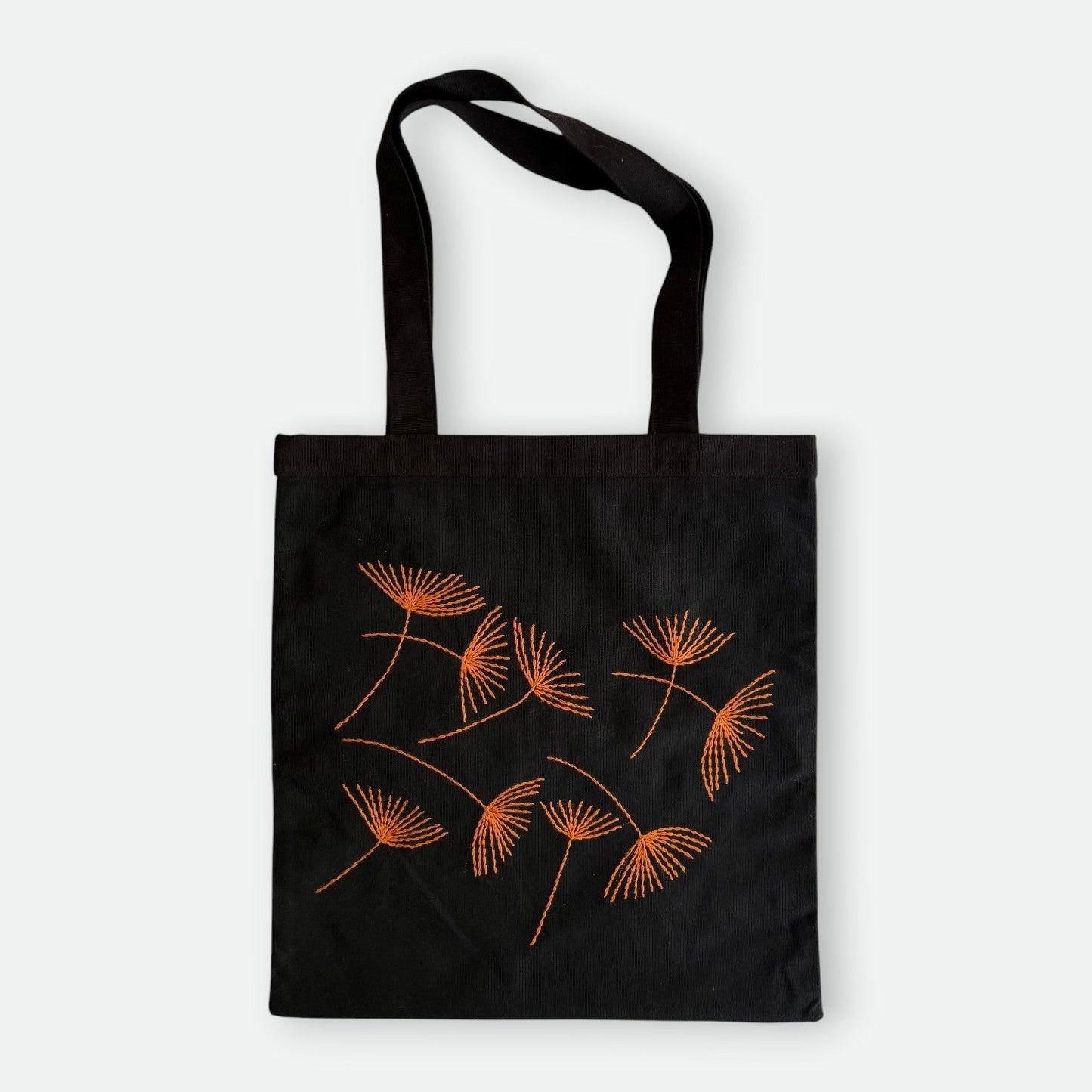 Black canvas tote bag with hand-embroidered orange papyrus design, fair trade handmade
