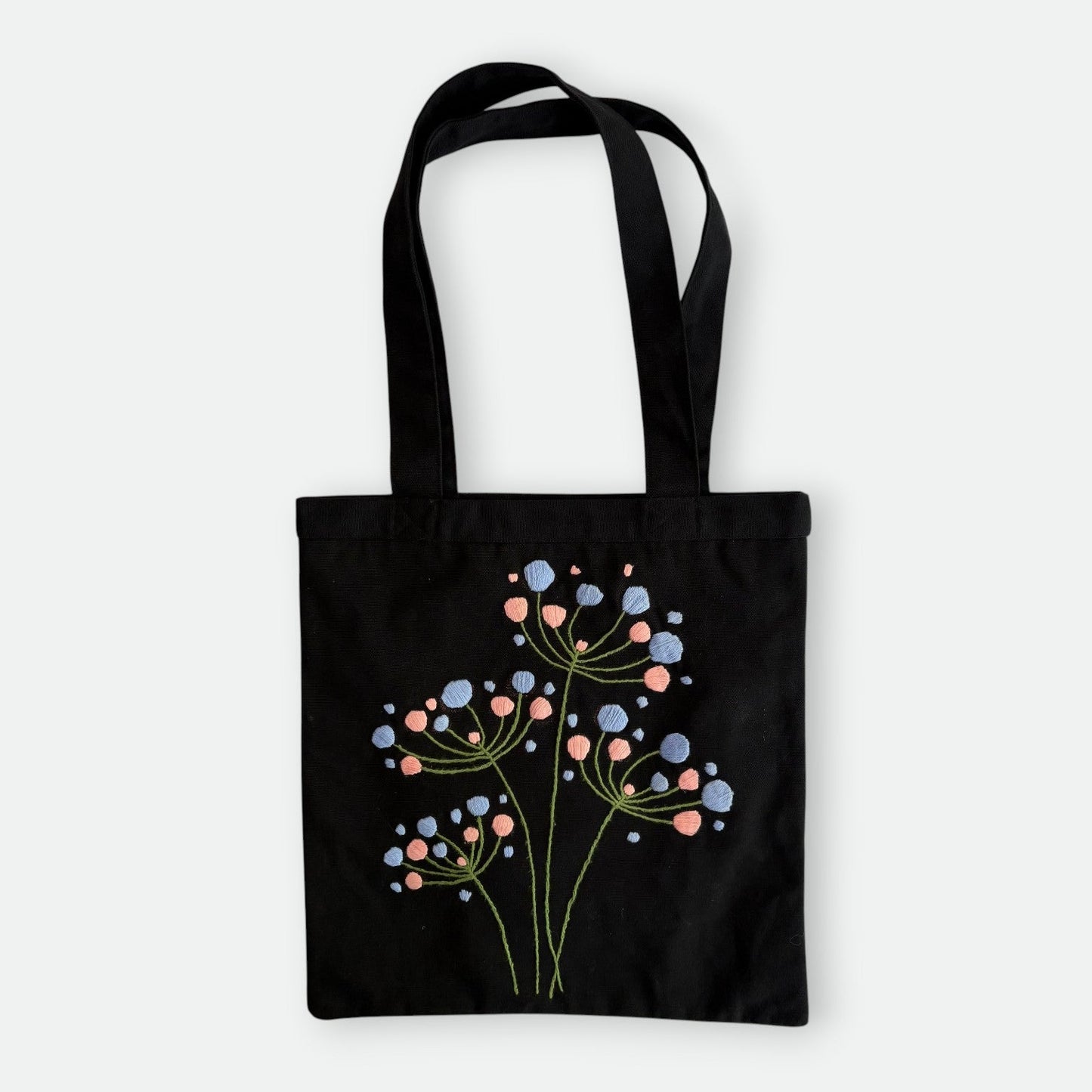 Handmade black tote bag with hand-embroidered light blue and pink hydrangea, fair trade