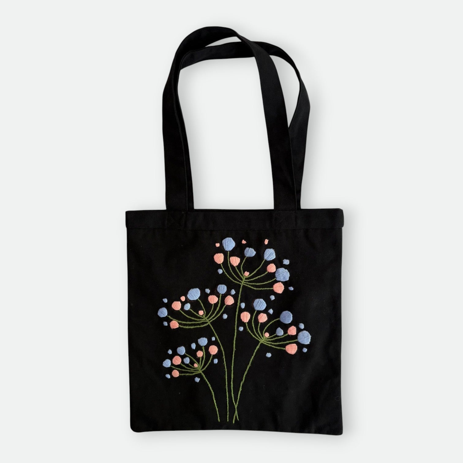 Handmade black tote bag with hand-embroidered light blue and pink hydrangea, fair trade
