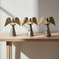 Three sustainable upcycled metal angel-shaped candle holders with gold and silver designs